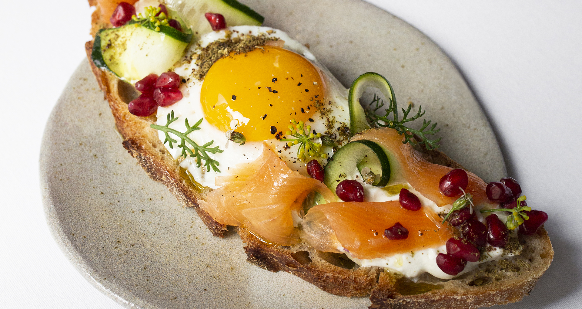 Toast, œuf au plat, grenade, courgette et truite